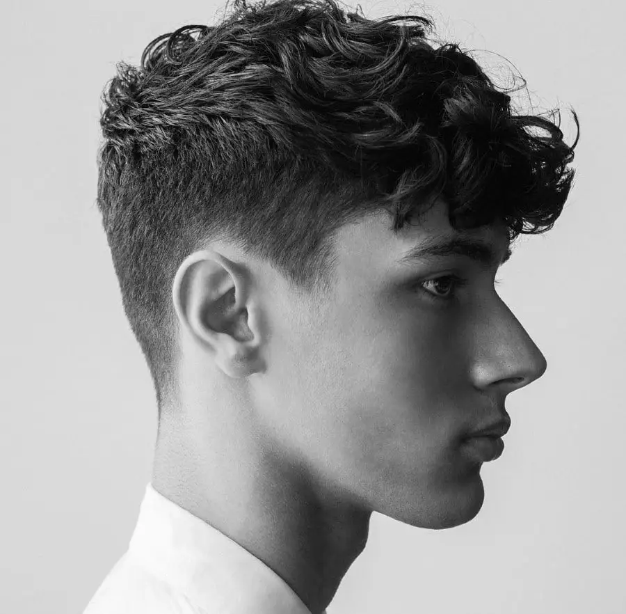 Black and white side profile of a young person with short wavy hair.